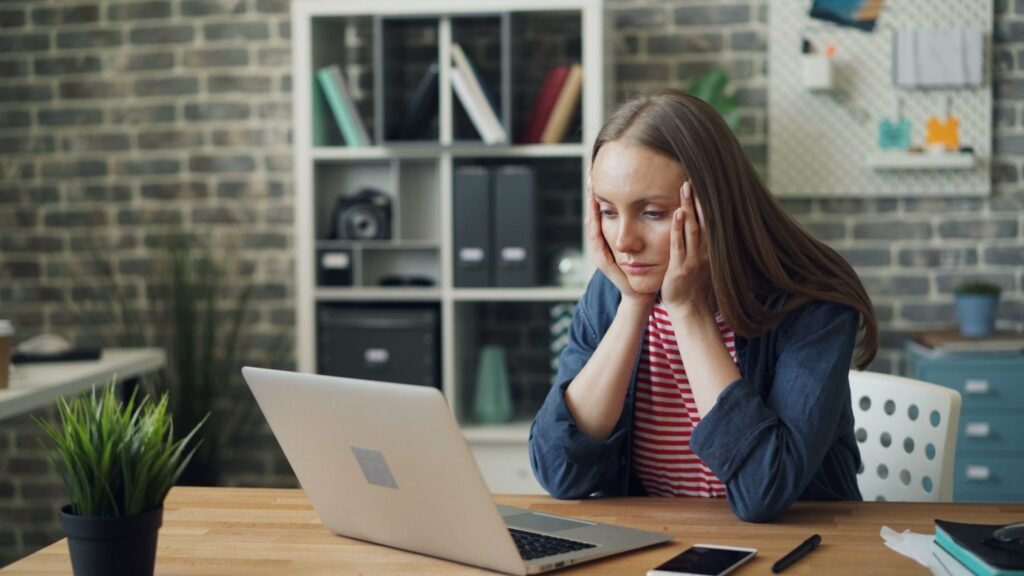 A worried woman looking at her laptop after finding a fake job offer