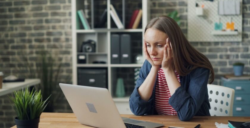 A worried woman looking at her laptop after finding a fake job offer
