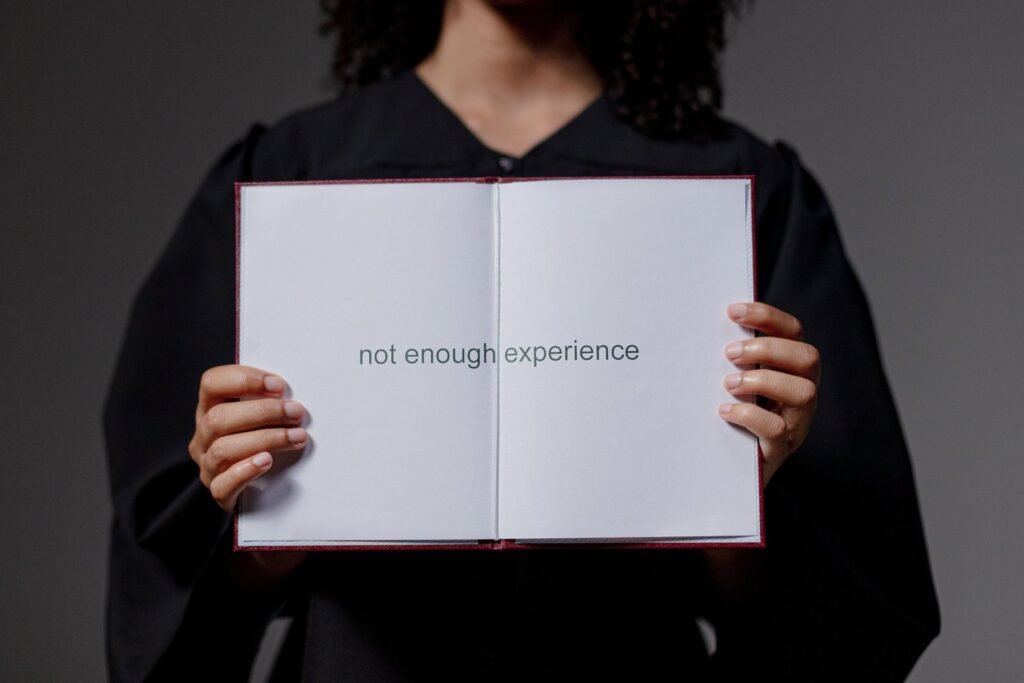 First job with no experience: graduate holding a book that says not enough experience