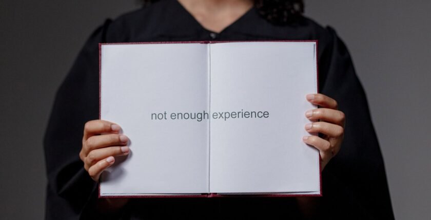 First job with no experience: graduate holding a book that says not enough experience